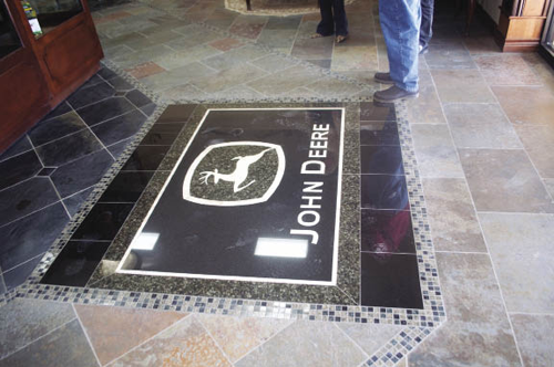 A custom-made John Deere logo made of black and green granite and yellow onyx is inlaid into the slate-top floor that’s used throughout the showroom. 