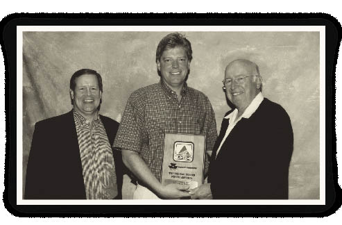 Don Millard of AGCO, and Cleve Buttars (ctr), owner of Agri-Service, accepts top volume dealer award for 2004 from Bob Ratliff, chairman and CEO of AGCO Corp.